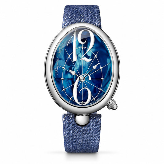 An oval wristwatch with a blue denim strap, a polished silver-tone case, and a blue dial featuring large white Arabic numerals 12 and 6 over a starburst pattern.