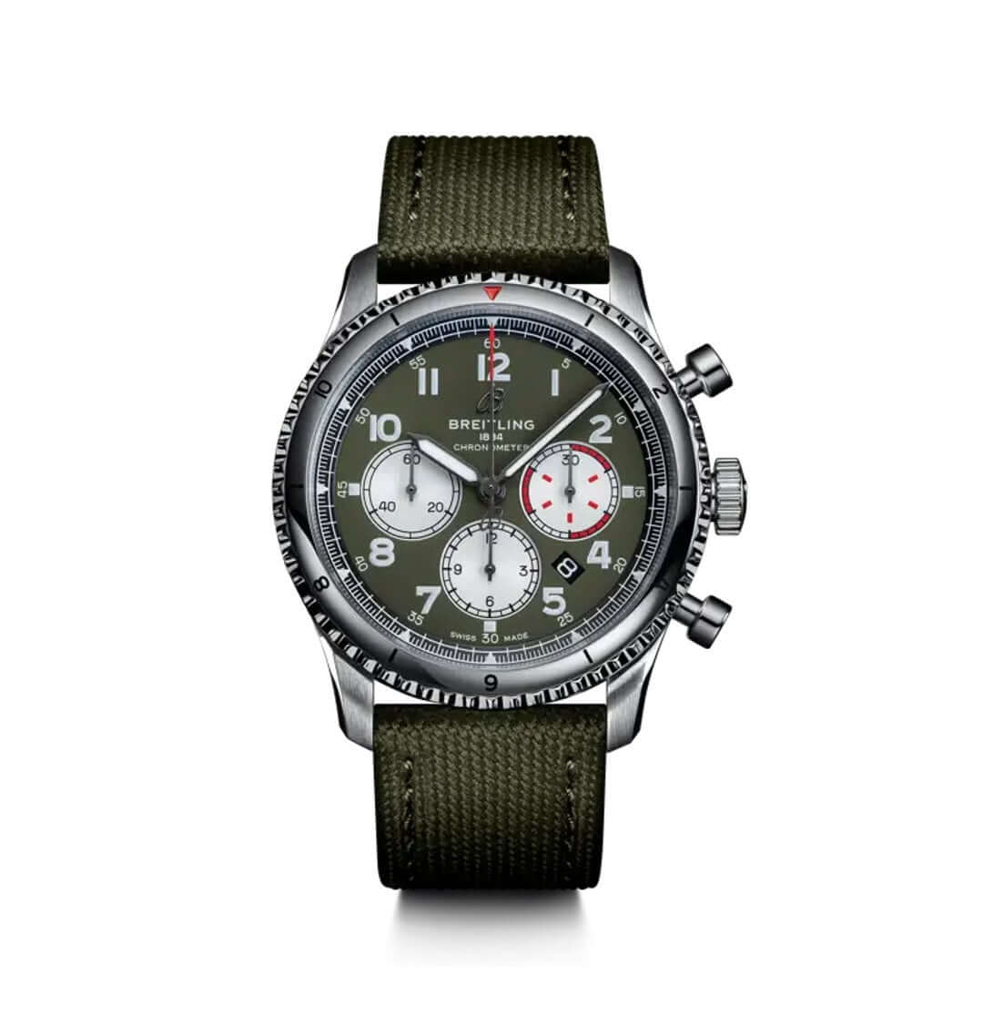 A Breitling chronograph watch with an olive green fabric strap, a silver-toned metal case, and a dark green dial with white and red accents.