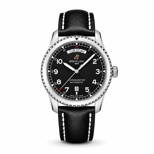 A Breitling Aviator 8 Automatic with a stainless steel case, black dial featuring white Arabic numerals, day and date window, and a black leather strap with white stitching.