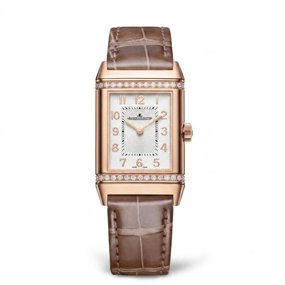 Jaeger-LeCoultre Reverso watch with a rose gold-tone rectangular case, silver dial with Arabic numerals, stone-set accents, and brown leather strap.