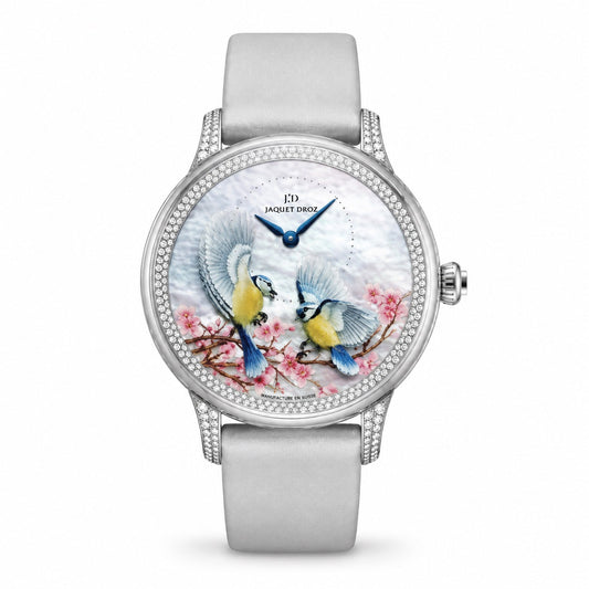 Jaquet Droz watch with a silver-tone case, stone-set bezel, dial depicting two birds among pink blossoms, blue hands, and a light grey strap.